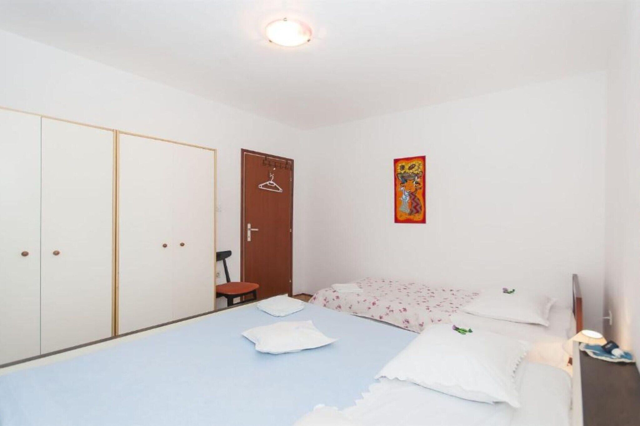 Ein Schlafzimmer mit einem Einzelbett, einem Kleiderschrank, einer Tür und einer Wanddekoration.