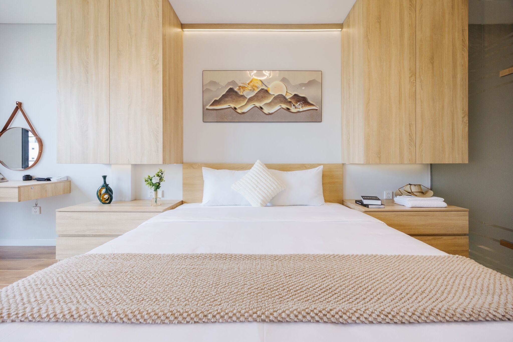 Une chambre moderne avec un grand lit, une tête de lit en bois, des tables de chevet, un tableau accroché au mur et un miroir.