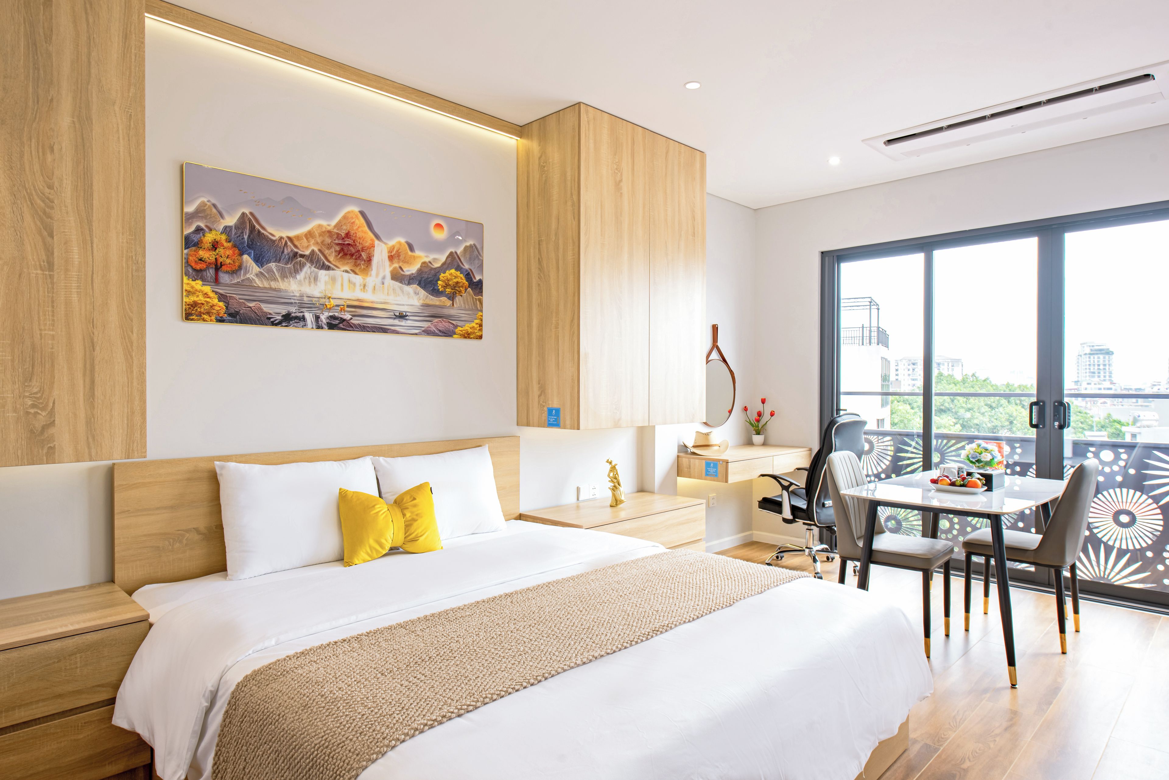 A hotel room with a bed, a desk, a chair, and a large window.