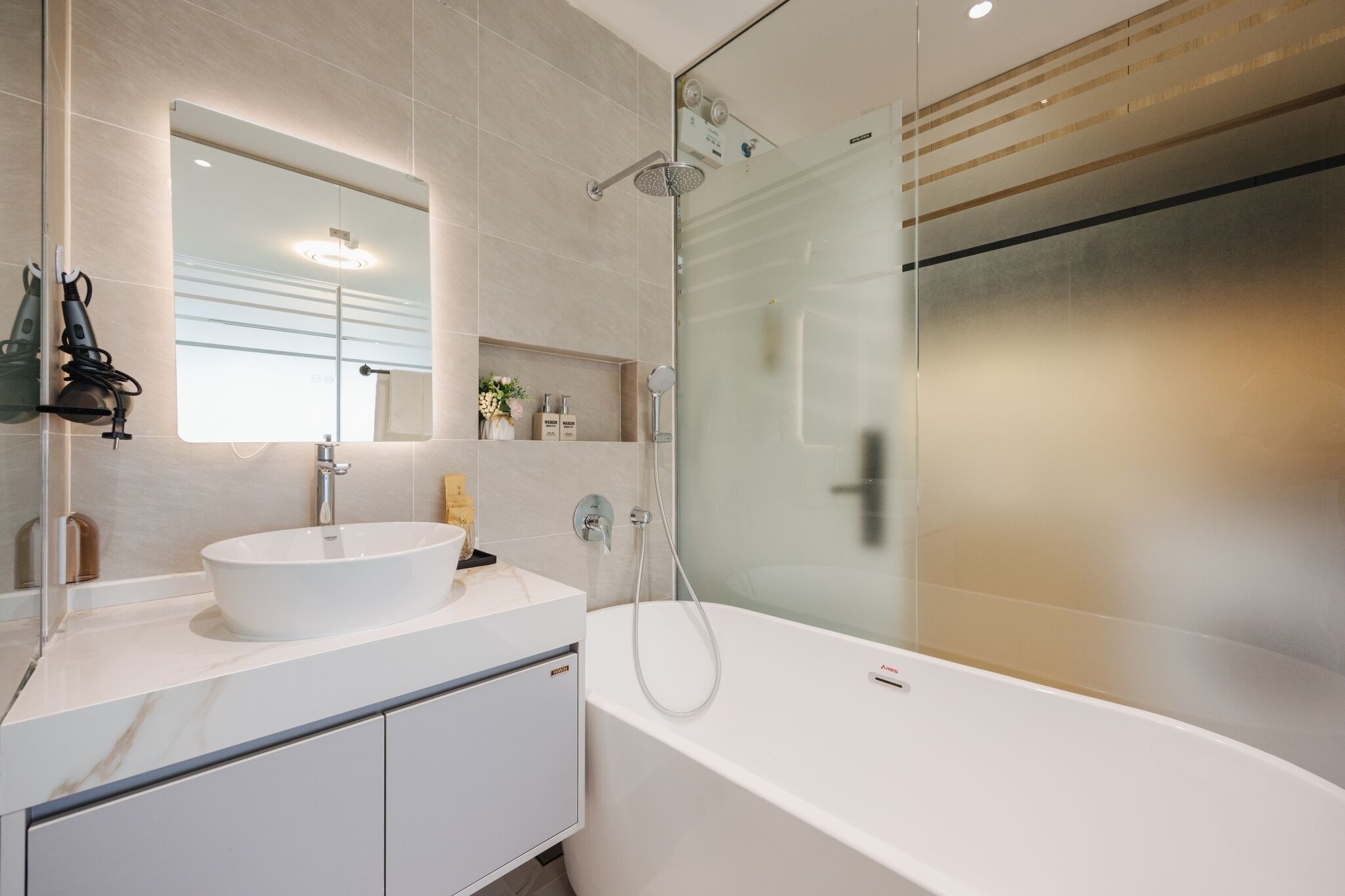 A modern bathroom with a white sink, a large mirror, and a glass-enclosed shower area.