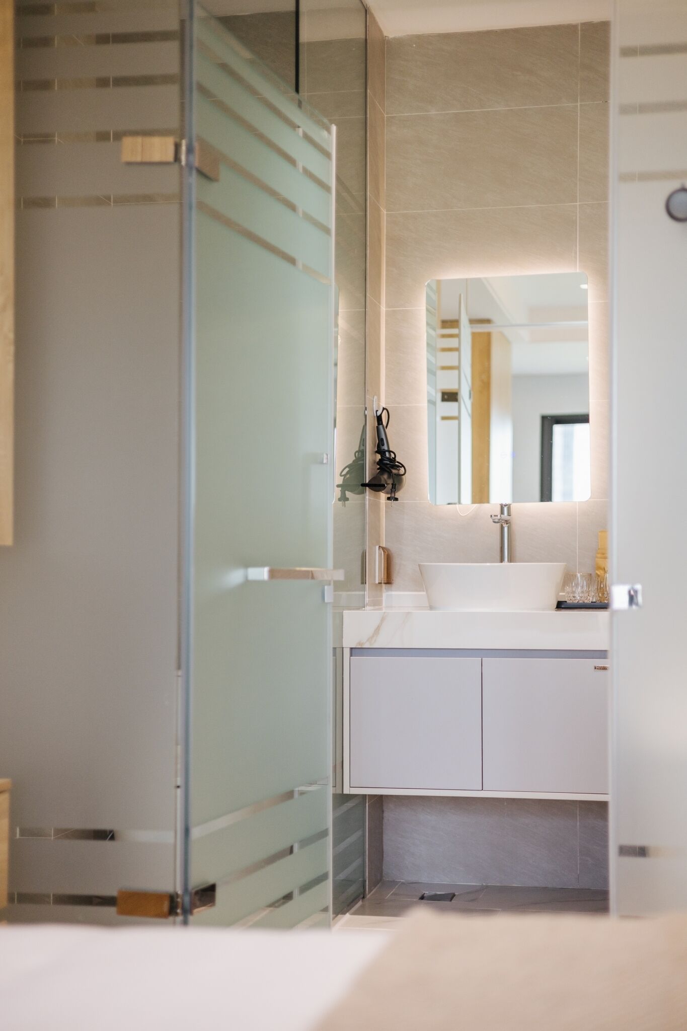 A modern bathroom with a glass shower enclosure, a white sink, and a large mirror above it.