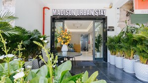 L'ingresso di Madison Urban Stay, dal design moderno, con porta in vetro, piante da interno e un'accogliente area di ricevimento.