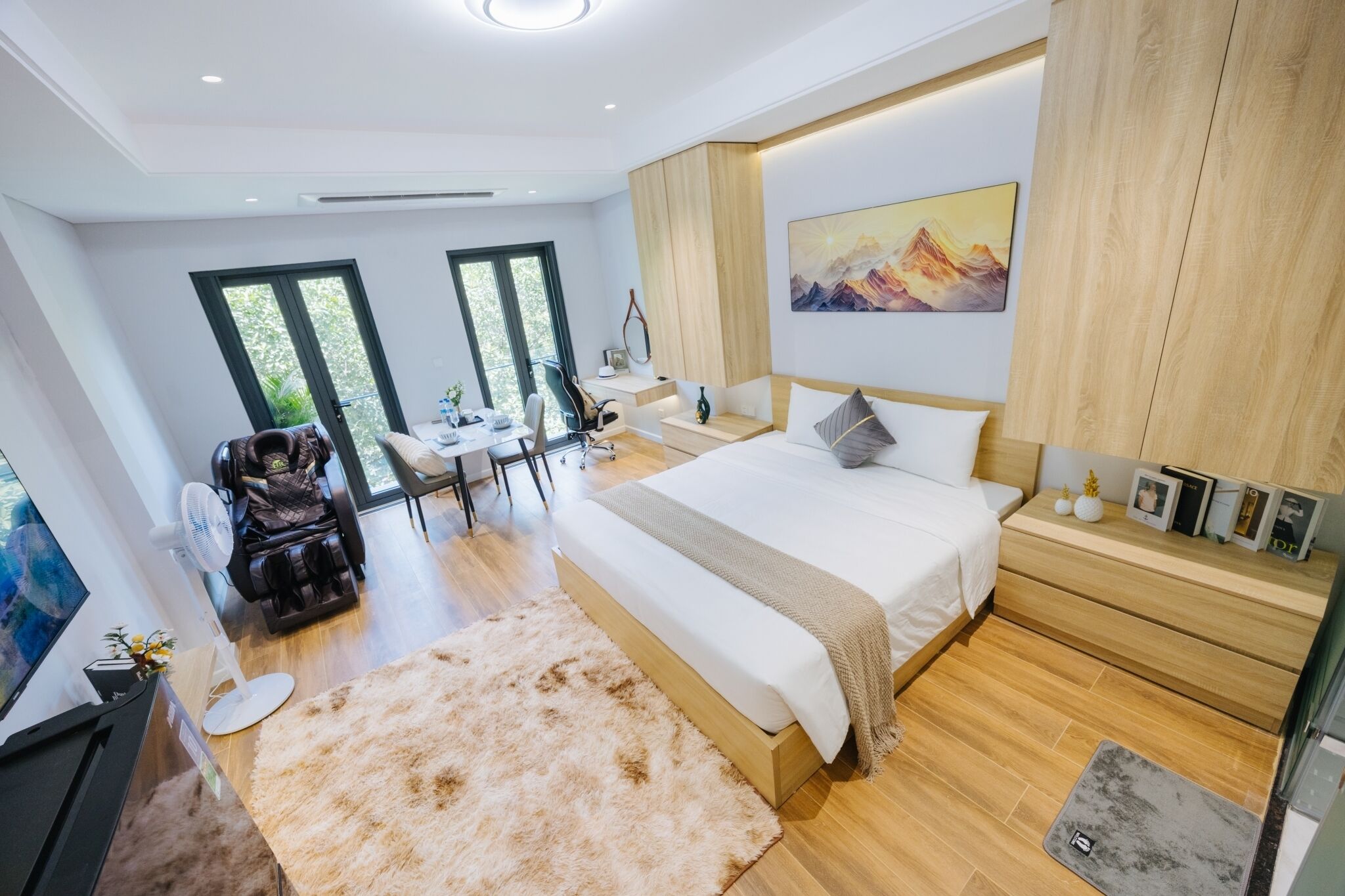 Un dormitorio moderno con una cama grande, una silla de masaje, un escritorio y vistas al exterior.