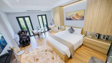 Un dormitorio moderno con una cama grande, una silla de masaje, un escritorio y vistas al exterior.