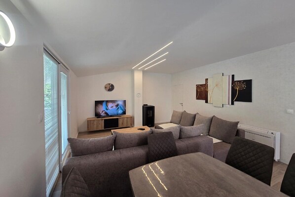 A modern living room with a sofa set, a flat-screen TV, and artwork on the wall.