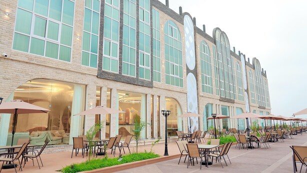 A hotel exterior with outdoor seating, large windows, and a brick facade. - Dreamland Resort Salalah (Salalah)
