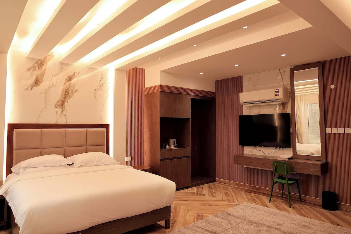 A modern bedroom with a large bed, built-in wardrobe, and a television.