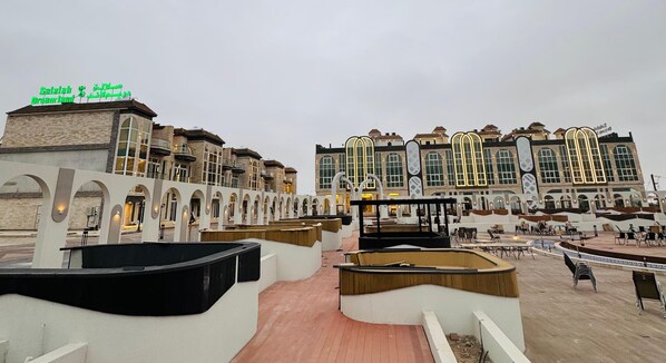 Un hotel con diseño moderno, que cuenta con un amplio espacio exterior con mobiliario y una piscina.