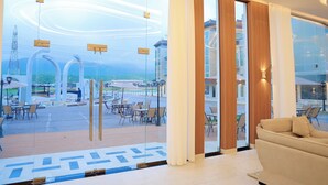 A modern hotel room with large windows, a sofa, and a view of the outdoor seating area. - Dreamland Resort Salalah (Salalah)