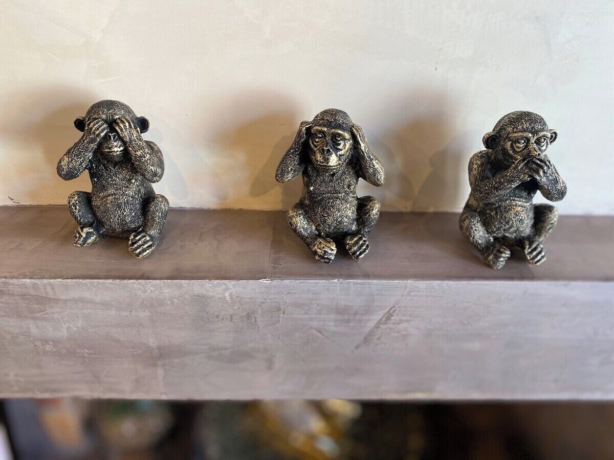 Trois statuettes de singes sont posées sur une étagère.
