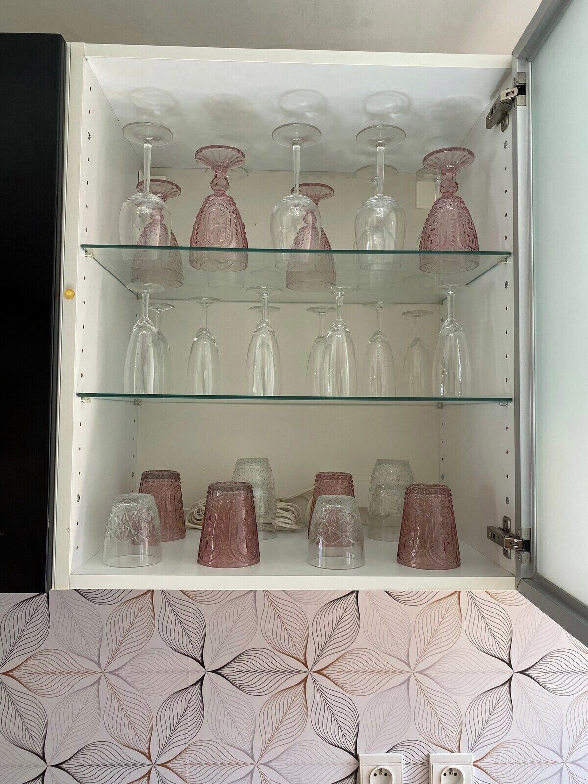 Een kast met meerdere planken, gevuld met diverse glazen.