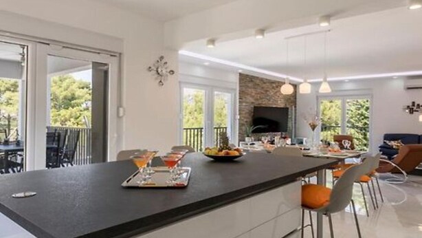 Een moderne keuken met een centraal eiland, barstoelen en een eethoek met een tafel en stoelen.
