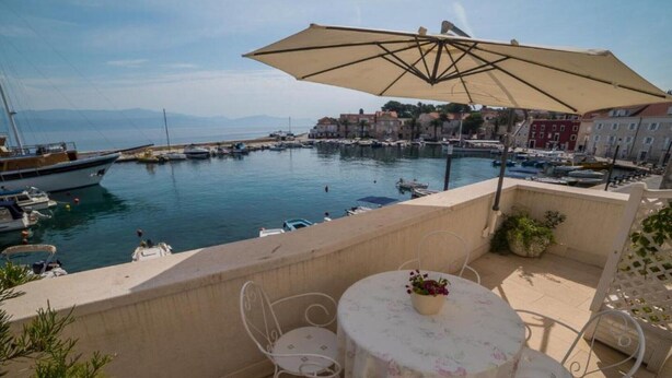 Una terraza con mesa y sillas, con vistas a un puerto deportivo con barcos y edificios al fondo.