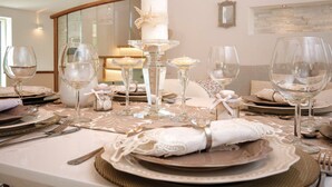 A formal dining table set with clear glassware, white napkins, and a central candle.