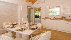 A modern kitchen with white cabinets, a wooden countertop, and a window overlooking a garden.
