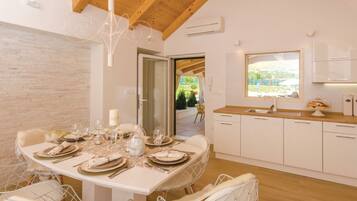 Een moderne keuken met witte kastjes, een houten aanrechtblad en een raam met uitzicht op een tuin.