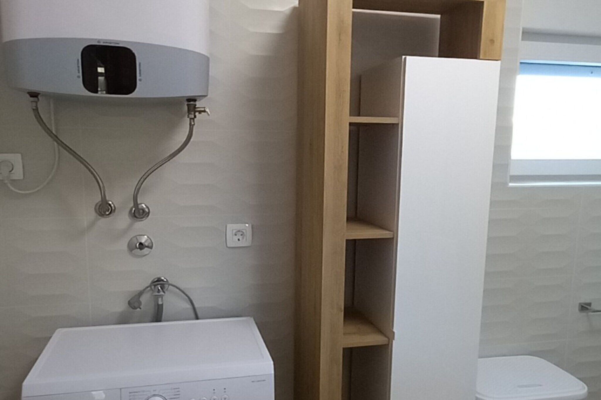 A bathroom with a white sink, a towel rack, and a wooden shelf unit.