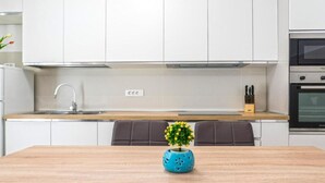 A modern kitchen with white cabinets, a wooden countertop, a sink, and an oven. - Two Bedroom Apartment With Private Pool (Privlaka)