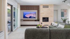 Ein modernes Wohnzimmer mit Fernseher, Kamin und einer Couch.