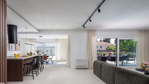 Ein modernes Wohnzimmer mit Küchenbereich, einer Couch und einem Esstisch mit Stühlen.