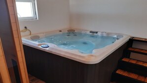 Un bain à remous dans une pièce au plancher en bois et dotée d’une fenêtre.