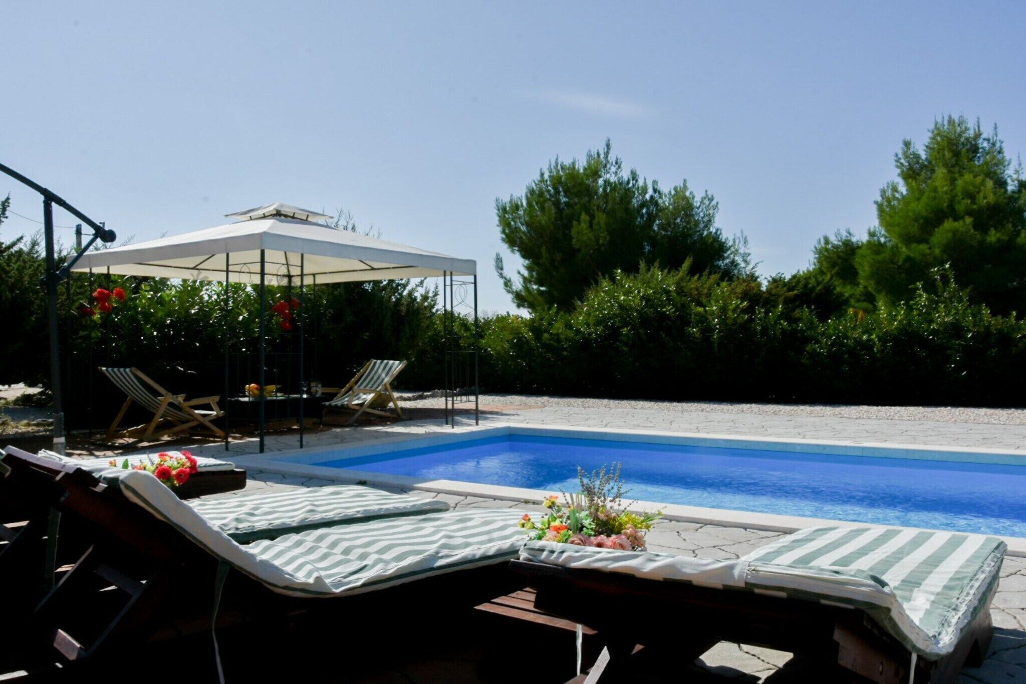 A swimming pool with lounge chairs and a covered seating area.