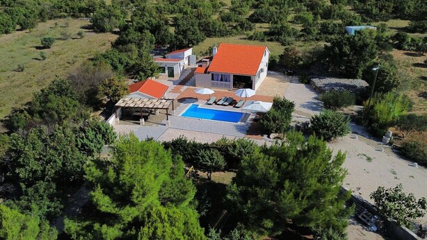 Une maison avec une piscine, entourée d’arbres et d’un jardin.