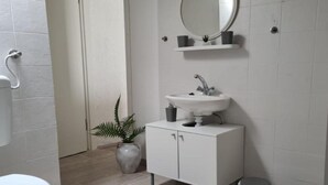 Un bany modern amb un rentapins, mirall i armari blancs.