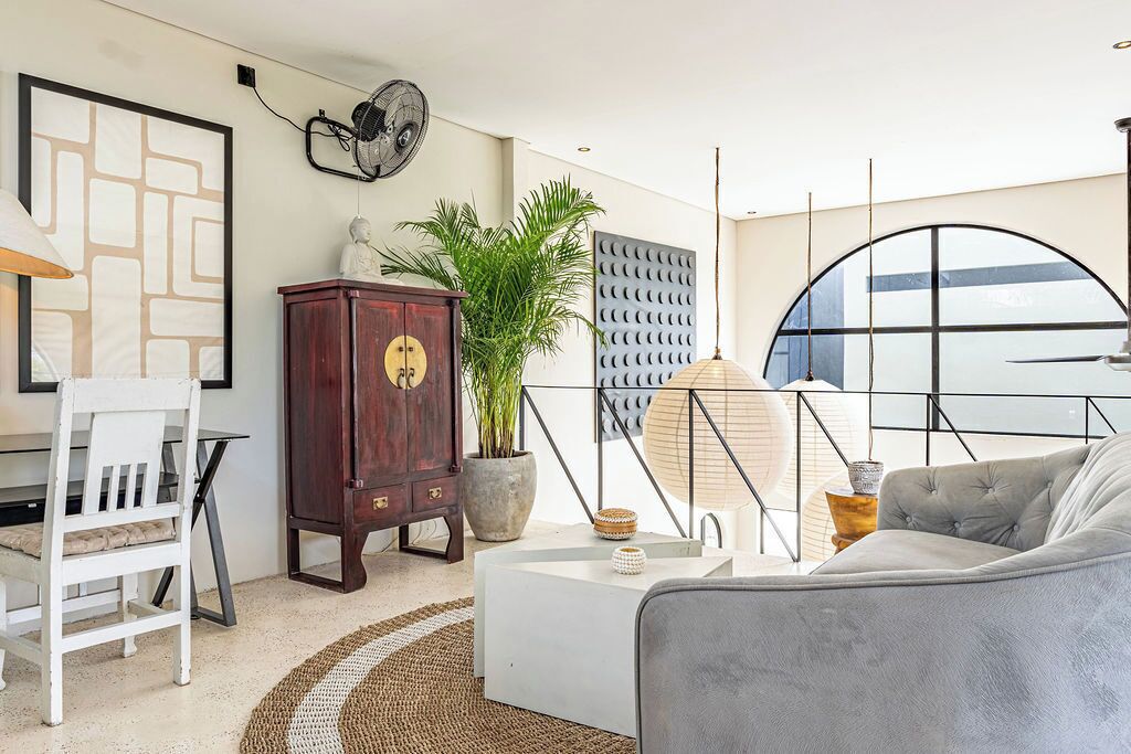Un salon moderne avec un canapé blanc, un meuble en bois, une plante en pot et une grande fenêtre donnant sur un beau paysage.