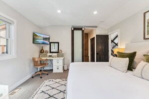 Ein Schlafzimmer mit Bett, Schreibtisch, Stuhl und Fernseher an der Wand.