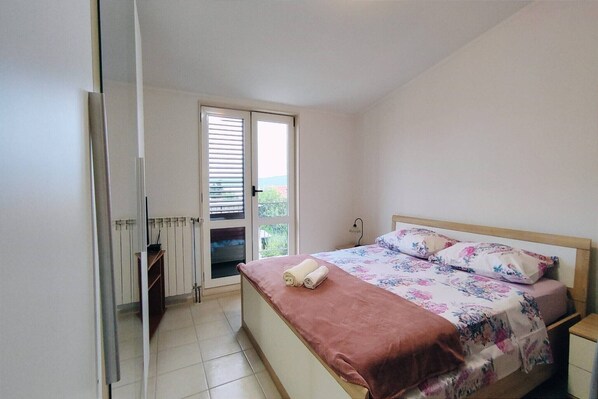 Ein Schlafzimmer mit Bett, Fenster und Heizkörper.