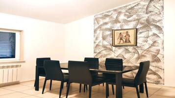 Ein Essbereich mit Tisch und Stühlen, ein Fenster mit Jalousien sowie eine Wand mit Muster und einem gerahmten Bild.
