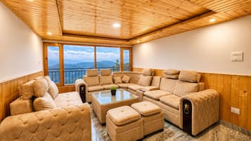A room with a wooden ceiling, large windows with a mountain view, and a sectional sofa.