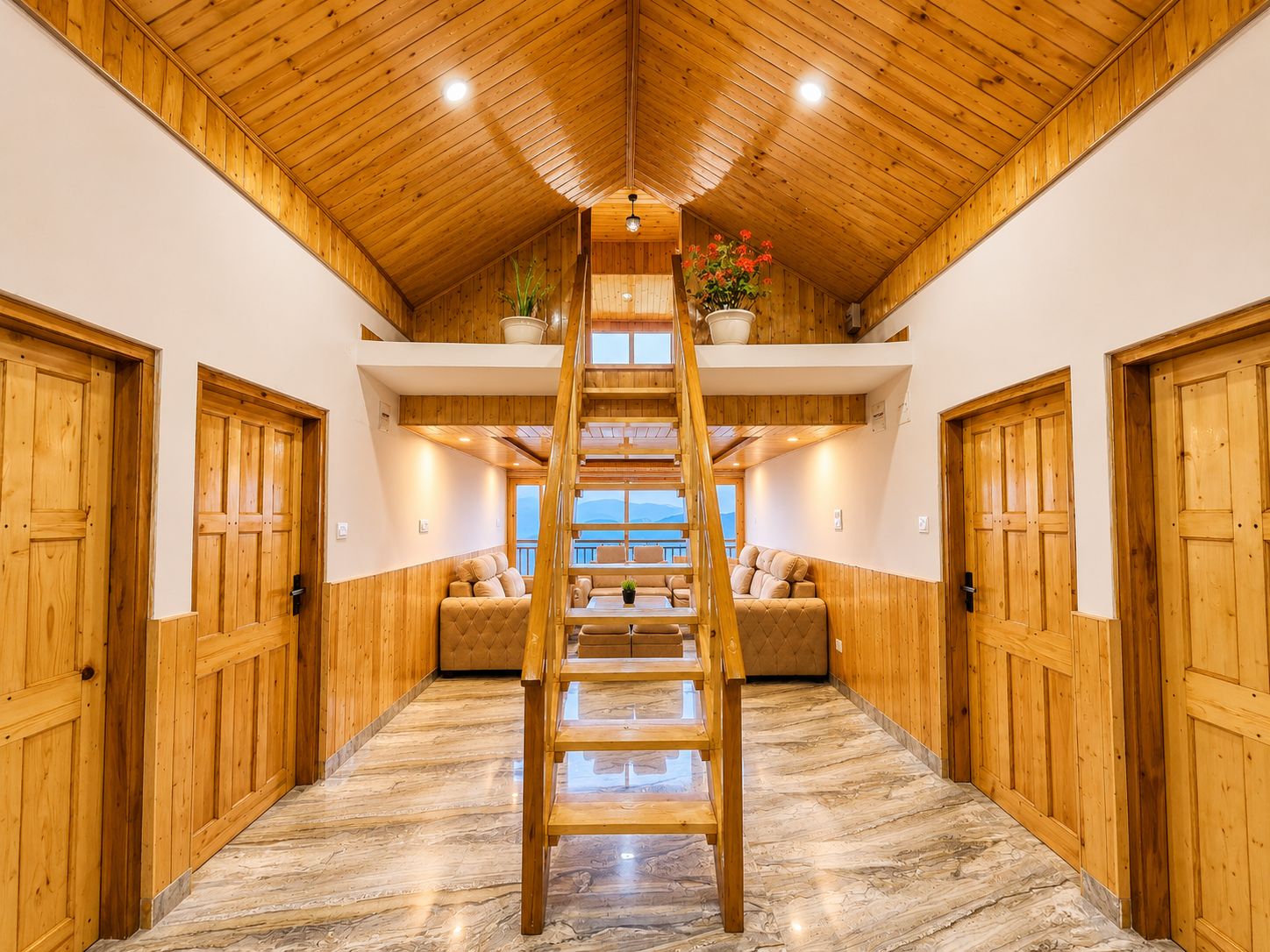 Un intérieur en bois avec un escalier central en bois, un canapé et une vue par une fenêtre.