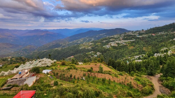 A mountainous landscape with terraced fields and scattered buildings. - The Kufri House (Theog)