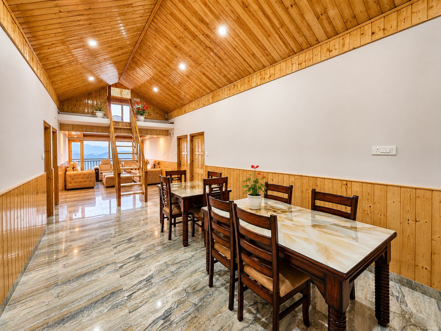 A spacious dining area with a wooden table and chairs, a staircase leading to an upper level, and a view of the outdoors.