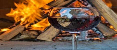 A glass of red wine in front of a fire.