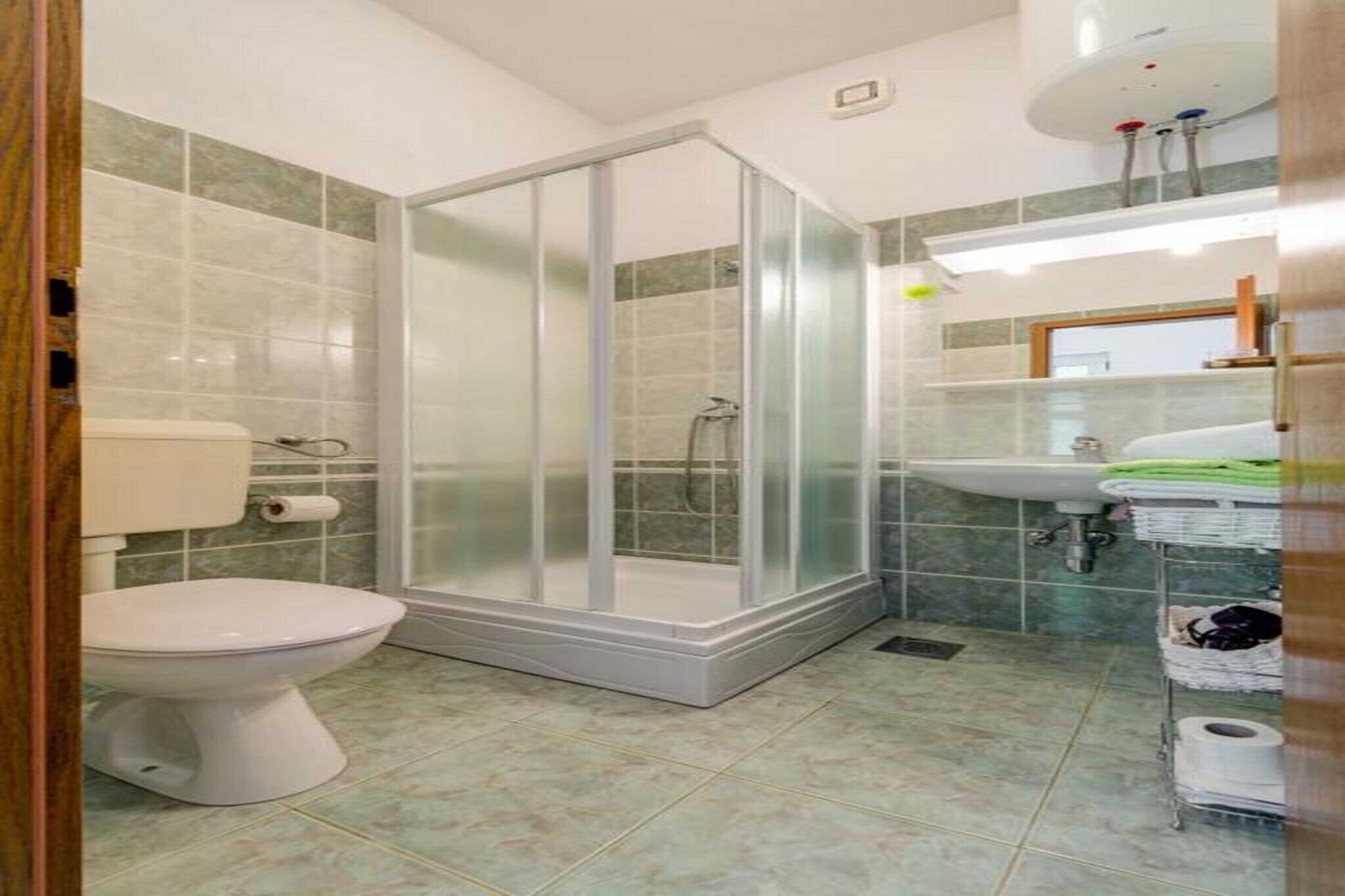 A bathroom with a toilet, a glass-enclosed shower, and a sink with a mirror above it.