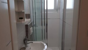 Un baño moderno con cabina de ducha de vidrio, lavamanos blanco y retrete.