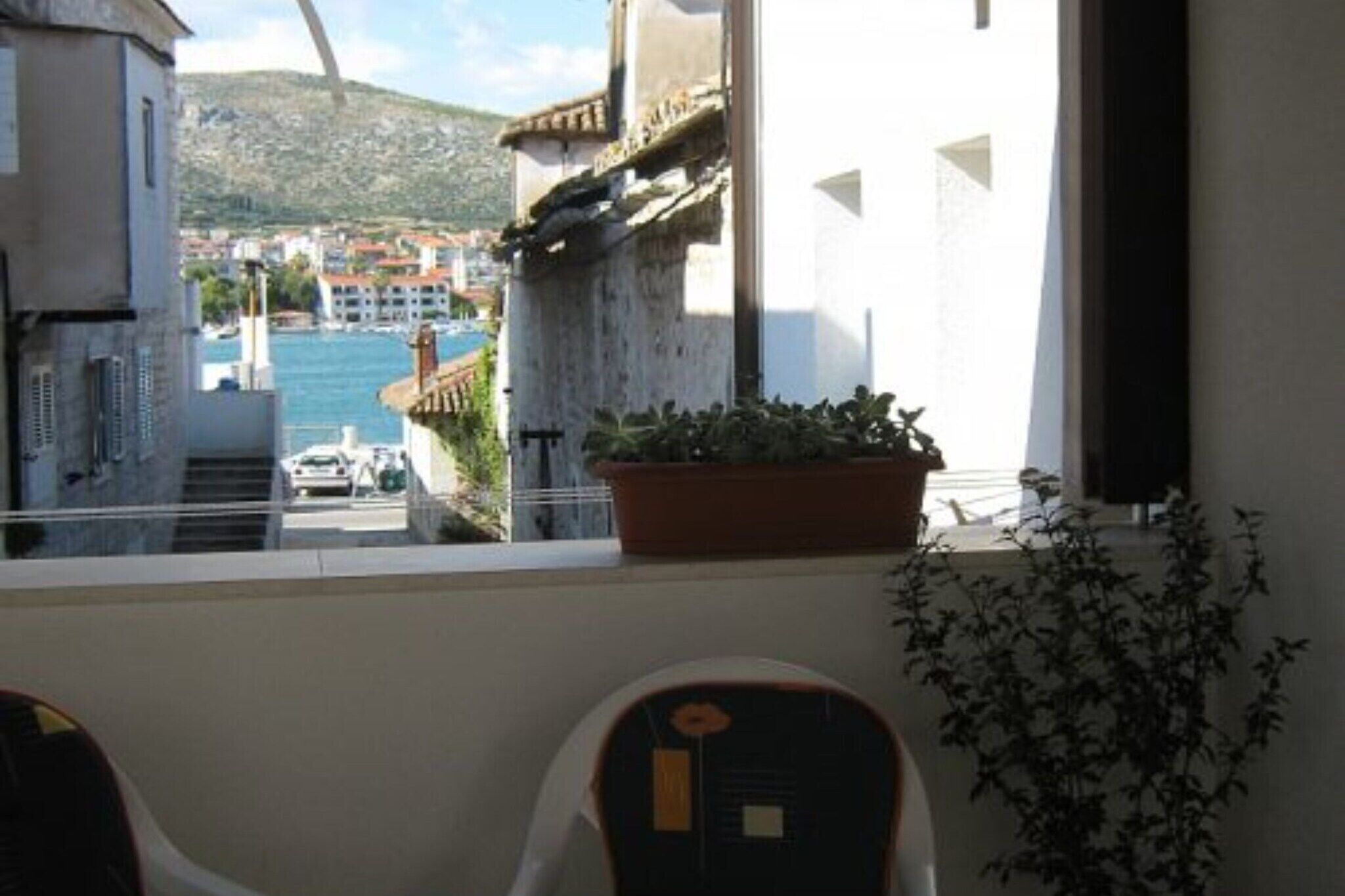 A balcony with a potted plant and a view of a coastal town.