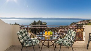 A balcony with a round table and chairs, overlooking a body of water and distant land. - Apartments Tafra - One Bedroom Apartment (Lokva Rogoznica)
