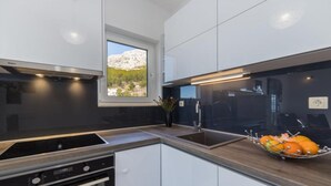 A modern kitchen with a built-in oven, a sink, and a window offering a view of the outdoors. - Apartments Tafra - One Bedroom Apartment (Lokva Rogoznica)