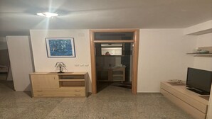 Ein Zimmer mit einem Holzkasten, einem Fernseher, einem gerahmten Bild an der Wand und einem Schrank mit Spiegel.