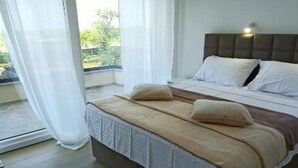 A bedroom with a bed, curtains, and a view of greenery outside. - Villa Sunrise with Outdoor Pool - 4 Bedroom & Pool (Šibenik)