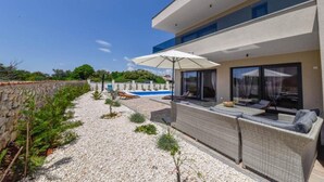 A modern house with a swimming pool, outdoor seating, and a stone wall. - Villa Sunrise with Outdoor Pool - 4 Bedroom & Pool (Šibenik)