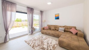 A living room with a sofa, a rug, and a painting on the wall. - Villa Sunrise with Outdoor Pool - 4 Bedroom & Pool (Šibenik)