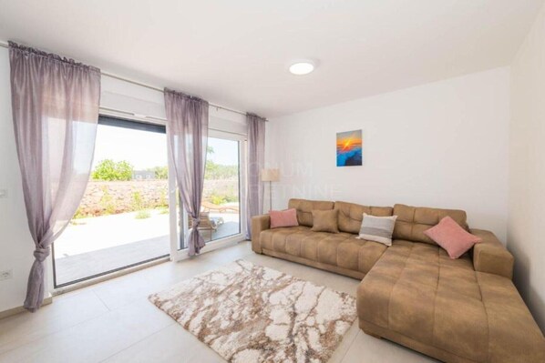 A living room with a sofa, a rug, and a painting on the wall. - Villa Sunrise with Outdoor Pool - 4 Bedroom & Pool (Šibenik)