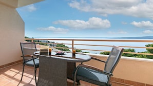 A balcony with a table and chairs, overlooking a body of water and distant land.