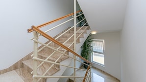 A staircase with wooden handrails, marble steps, and a potted plant.