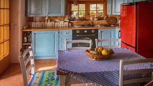 Uma cozinha com armários azuis, uma geladeira vermelha e uma mesa com uma cesta de frutas.